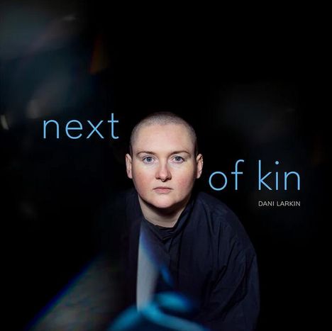 Texte: "next of kin", "DANI LARKIN". Jemand mit kurz geschorenem Kopf blickt direkt nach vorne.