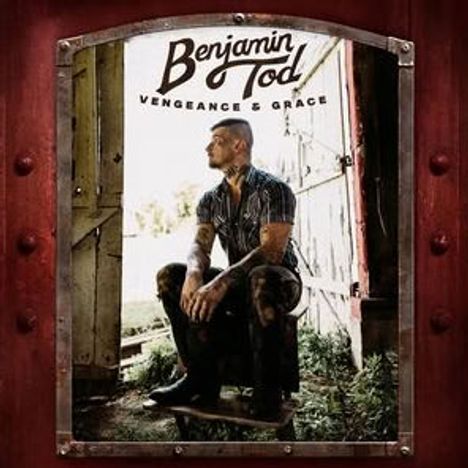 „Benjamin Tod Vengeance & Grace“. Ein Mann sitzt nachdenklich in einer geöffneten Scheunentür, umgeben von Natur.