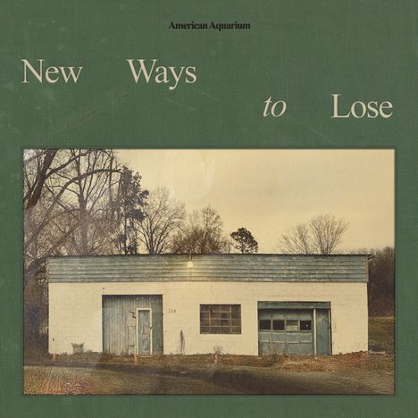 Texte: "American Aquarium", "New Ways to Lose". Ein altes Gebäude, weiß, türkisfarbene Türen, karge Bäume im Hintergrund.