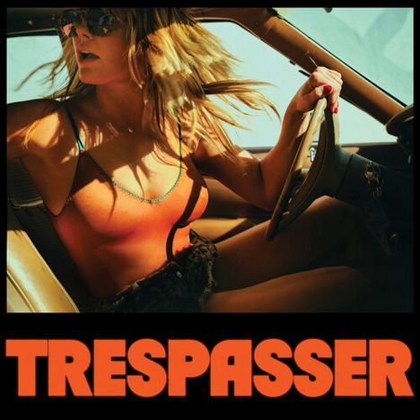 Text "TRESPASSER" in großen orangefarbenen Buchstaben unten. Frau mit Sonnenbrille im Auto bei sonnigem Licht.