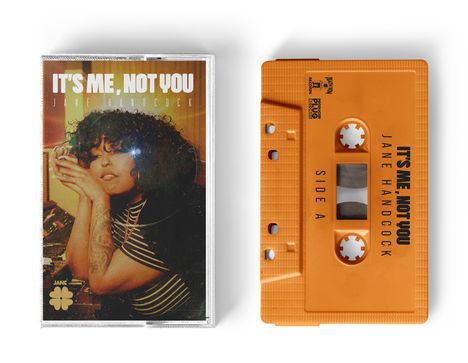 Text: "IT'S ME, NOT YOU" und "JANE HANDCOCK". Eine Frau mit Locken auf einem Musikalbum-Cover neben einer Kassette.