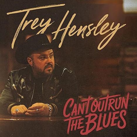 Text: "Trey Hensley" oben, "Can't Outrun the Blues" unten. Ein Mann mit Hut und Bart sitzt nachdenklich an einem Tresen.