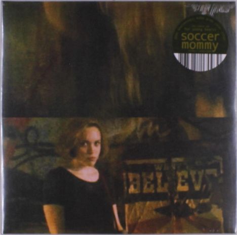Text oben in einem runden Aufkleber: „soccer mommy“. Unten ein Graffiti mit dem Wort „BELIEVE“. Junge Frau im Vordergrund.