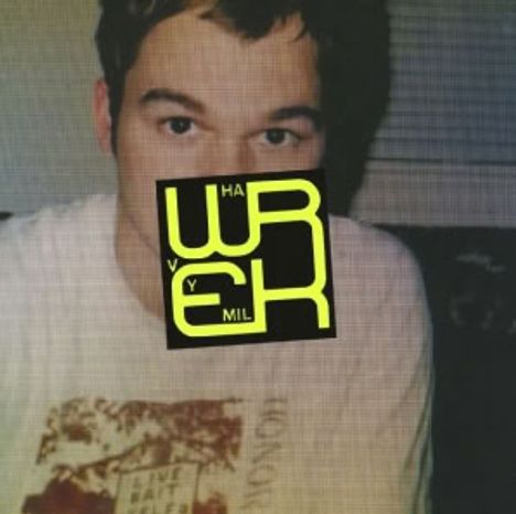 Ein Mann mit kurzem Haar, teilweise verdeckt von einem stilisierten, gelben Text: "WREK Y HAV MIL".