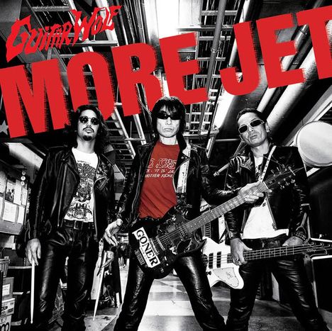 "MORE JET" in großen roten Buchstaben, darunter drei Männer in Lederjacken mit Gitarren in einem industriellen Raum.