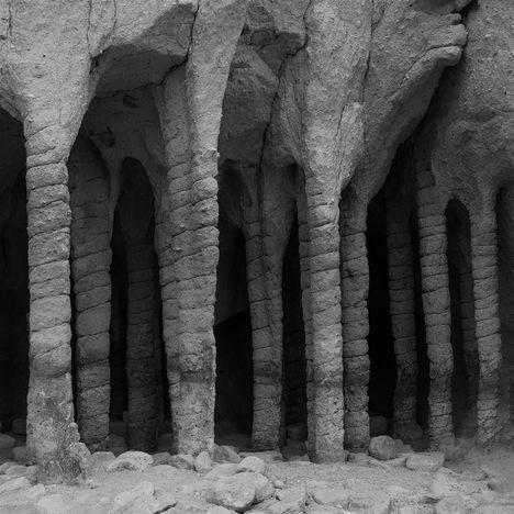 Steinige Säulen bilden eine natürliche Struktur in einer Höhle. Die Oberfläche ist rau und dunkel, die Umgebung wirkt mystisch.