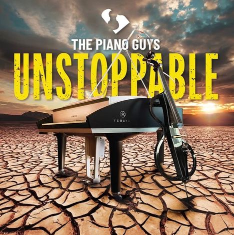 "The Piano Guys, Unstoppable" in großen Buchstaben über einem Piano und Cello auf trockener, rissiger Erde bei Sonnenuntergang.