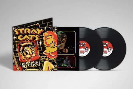 Text: "STRAY CATS RUMBLE IN BRIXTON." Comic-Stil-Cover mit einer Katze und Frau, zwei Vinyl-Schallplatten.