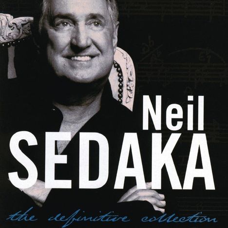 Text: Neil Sedaka, the definitive collection. Schwarz-weiß Foto eines lächelnden Mannes auf verziertem Stuhl.