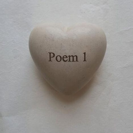 Der Text "Poem 1" steht auf einem herzförmigen Stein vor hellem Hintergrund.
