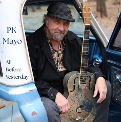 Texte: "PK Mayo All Before Yesterday." Ein Mann sitzt in einem offenen Auto und hält eine resonator Gitarre. Er trägt einen Hut.
