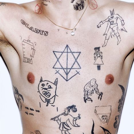 Verschiedene Tätowierungen auf dem Oberkörper: "GLADYS", eine Batterie, ein Stern aus zwei Dreiecken und diverse Figuren.