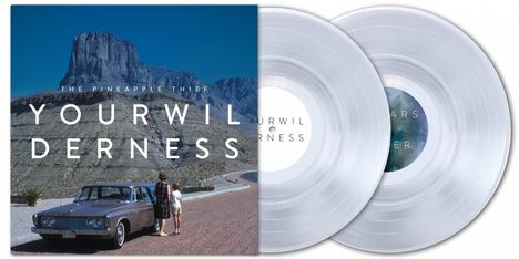 "THE PINEAPPLE THIEF YOUR WILDERNESS" auf einem Albumcover mit Auto vor Bergen und zwei transparenten Schallplatten.
