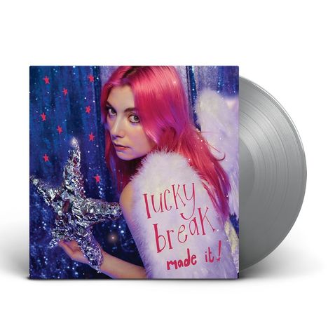 „Lucky break, made it!“ steht in rosa Schrift auf rosa Haaren. Eine Person mit Engelsflügeln hält einen silbernen Stern.