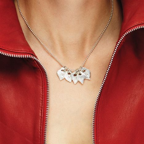 Anhänger mit Buchstaben H-A-P-P-Y auf Halskette. Roter Lederjacke mit offenem Reißverschluss.