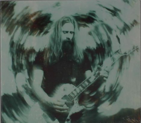 Keine Texte erkennbar. Ein Mann mit langen Haaren spielt Gitarre, umgeben von einem verschwommenen Wirbeleffekt.