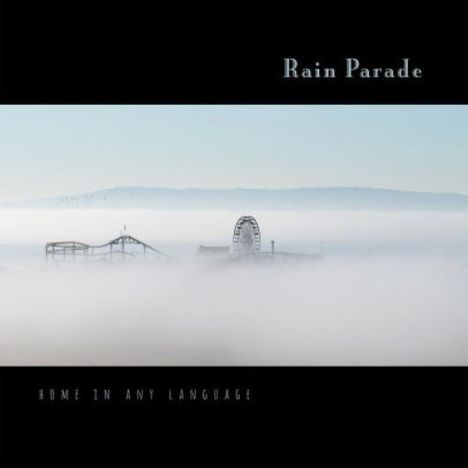 Oben steht "Rain Parade", unten "Home in Any Language". Im Nebel ein Riesenrad und eine Achterbahn.