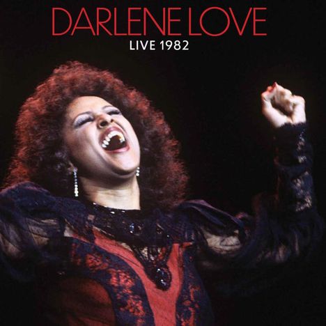 DARLENE LOVE, LIVE 1982. Frau singt leidenschaftlich mit erhobener Faust, trägt schwarzes und rotes Kleid.