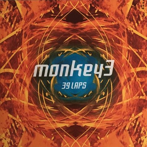 Text: "monkey3", "39 LAPS". Abstrakte, symmetrische Muster in warmen Farben, mit zentralem blauen Element.