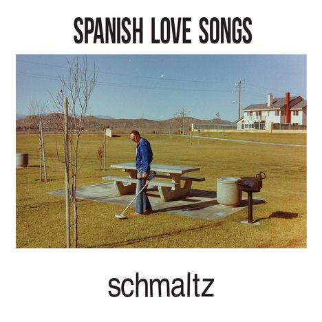 "SPANISH LOVE SONGS" oben, "schmaltz" unten. Ein Mann mit Metalldetektor in einem Park mit Tisch und Bäumen.