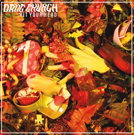 "DRUG CHURCH HIT YOUR HEAD" steht oben. Dschungel-Thema, Blätter, gelbe Hand, Geschenkboxen, goldene Kugel.