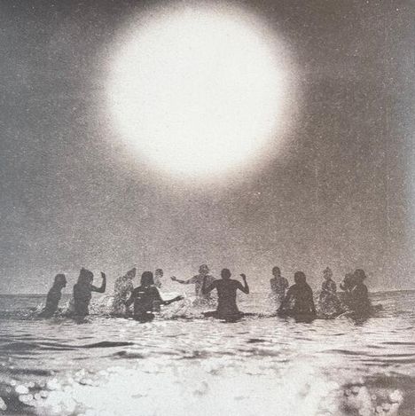 Menschen im Wasser bilden einen Kreis unter einer großen, hellen Sonne, die den Himmel dominiert.