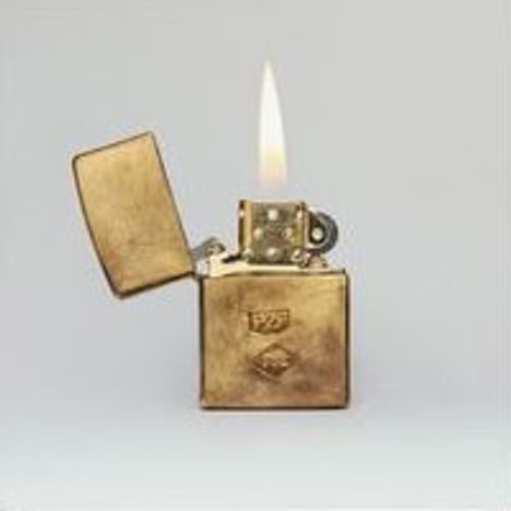 Ein goldenes Feuerzeug mit geöffneter Kappe, entzündeter Flamme, Emblemen auf der Vorderseite. Schlichter Hintergrund.