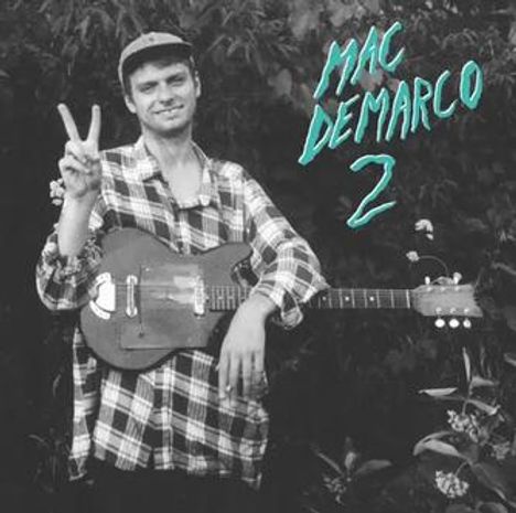 „MAC DEMARCO 2“ in türkisfarbenem Text. Person in kariertem Hemd hält Gitarre und zeigt Peace-Zeichen.