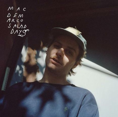 Text: "MAC DEMARCO SALAD DAYS". Eine Person mit Mütze steht im Schatten, vor einem hellen Hintergrund.