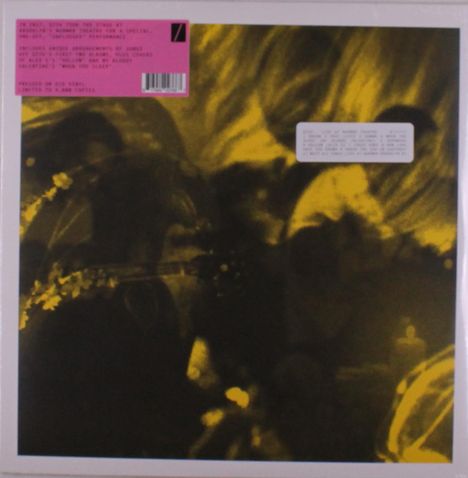 Ein rosa Etikett beschreibt eine Musikveröffentlichung auf rotem Vinyl, begrenzt auf 2.000 Exemplare. Unscharfer, gelb-schwarzer Hintergrund.