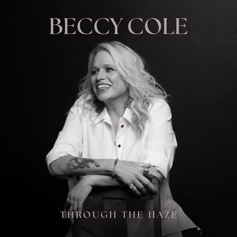"BECCY COLE" oben, "THROUGH THE HAZE" unten. Eine lächelnde Frau mit langen, blonden Haaren lehnt an einem Stuhl.