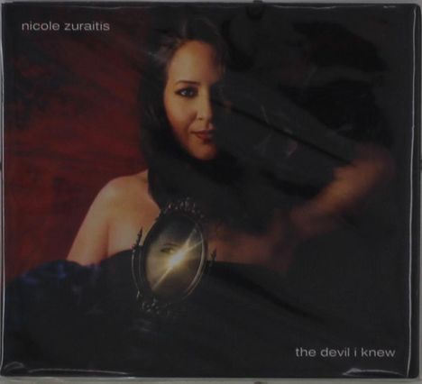 Oben links: "nicole zuraitis". Unten rechts: "the devil i knew". Frau mit einem ovalen Spiegel in der Hand, roter Hintergrund.