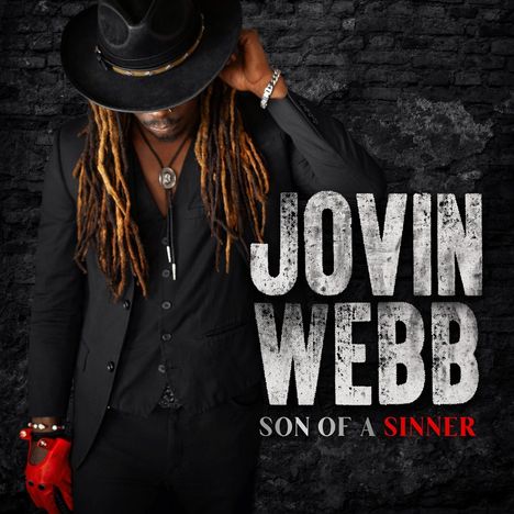 Text: "JOVIN WEBB SON OF A SINNER". Eine Person in schwarzem Anzug und Hut mit langen Dreadlocks auf dunklem Hintergrund.