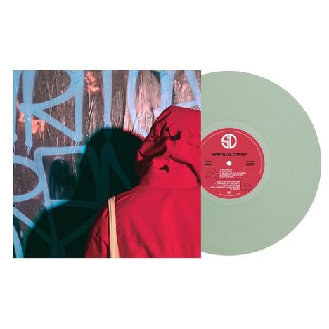 "Spiritual Cramp" auf einer Schallplatte mit Trackliste. Person in roter Jacke vor Graffiti. Vinyl in hellem Grün.