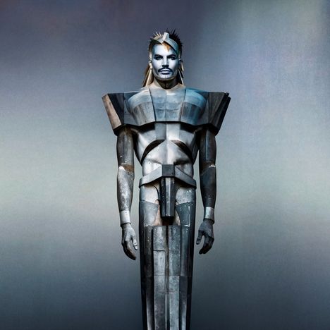 Illustration eines androgynen, humanoiden Wesens in futuristischer Rüstung mit kantigen Formen vor neutralem Hintergrund.