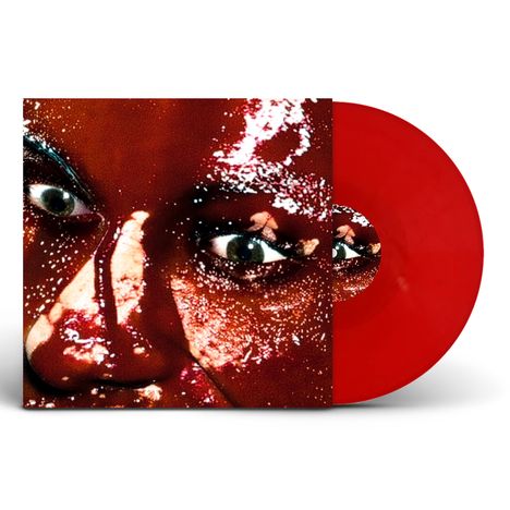 Nahaufnahme eines Gesichts mit glitzernder Haut, rotes Vinyl sichtbar daneben.