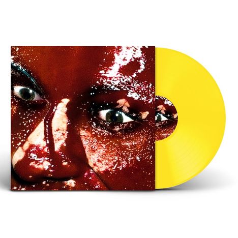 Ein leuchtend gelbes Vinyl mit einem Nahaufnahme-Gesicht, glitzernde Effekte und intensive Augen.
