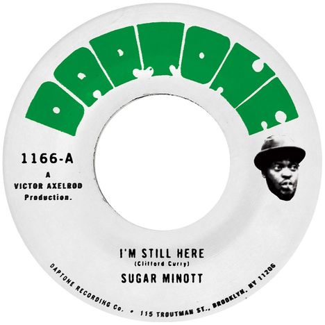 "Daptone" in grün über dem Etikett einer Schallplatte mit den Liedtiteln "I'M STILL HERE" von Sugar Minott. Kopf eines Mannes abgebildet.