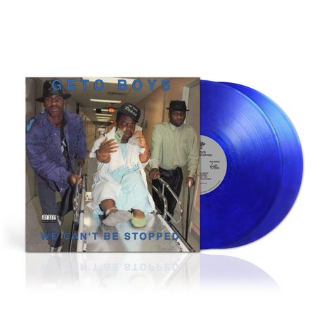 "GETO BOYS" oben, "WE CAN'T BE STOPPED" unten. Zwei Männer schieben einen Krankenhausrollstuhl durch einen Flur. Zwei blaue Schallplatten.