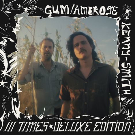 „GUM/AMBROSE“, „KENNY SMITH“, „iii TIMES DELUXE EDITION“. Zwei Personen stehen in einem Feld bei Sonnenuntergang.