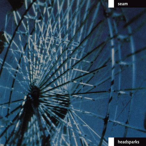 Text oben: "seam". Text unten: "headsparks". Verschwommenes Bild von einem Riesenrad bei Nacht in Blautönen.