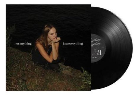 Texte: "not anything" links, "just everything" rechts. Eine Frau sitzt nachdenklich auf einem grasigen Untergrund.