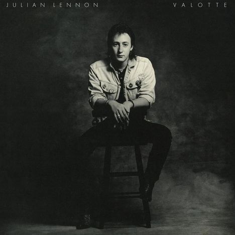 Text oben: "Julian Lennon", "Valotte". Eine Person sitzt auf einem Hocker, trägt eine Jeansjacke und blickt in die Kamera.
