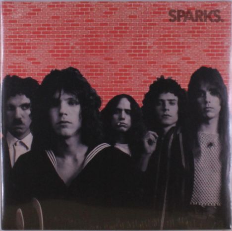 Der Text "SPARKS" ist oben rechts vor einer roten Ziegelmauer. Fünf Männer stehen in dunkler Kleidung davor.