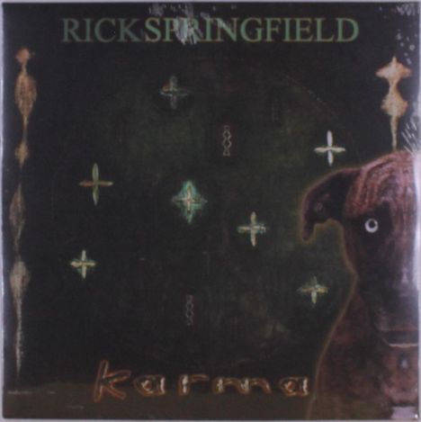 Text oben: "RICK SPRINGFIELD". Unten: "karma". Dunkle Illustration mit Kreuzsymbolen und einem Hund am rechten Rand.