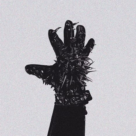 Stachelnbesetzter Handschuh in schwarz-weiß, dessen Handfläche nach vorne zeigt.