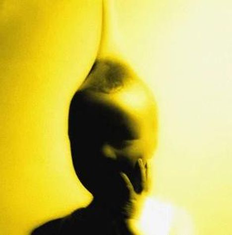 Ein gelbliches, abstraktes Bild eines Kindes mit unscharfen Konturen, das sein Gesicht mit der Hand berührt.