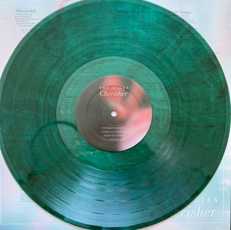 Auf der Schallplatte steht: "THE JULIES, Cherisher. Teenage Sadness, Love is a Paragon, Forever Song, Rooms." Sie ist grün.