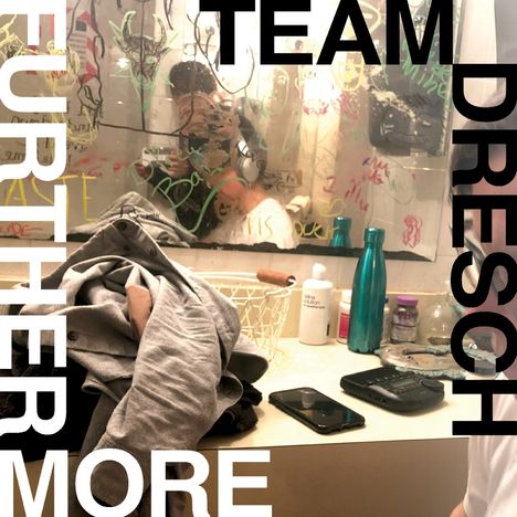 TEAM DRESCH, FURTHERMORE. Kleidung liegt auf einem Tisch vor einem Spiegel mit bunten Kritzeleien.