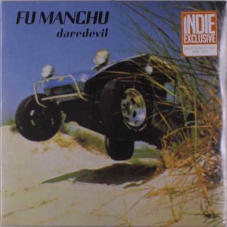 "FU MANCHU daredevil. INDIE EXCLUSIVE. Ein Auto springt über eine sandige Düne, während Äste im Wind wehen."